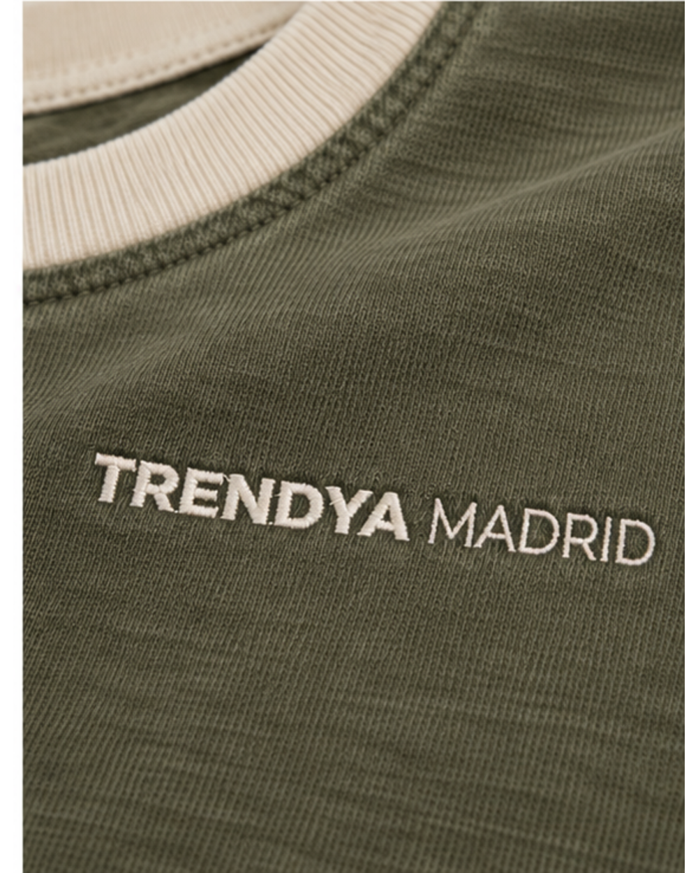 Detalle del cuello de canalé crema y del logotipo Trendya Madrid bordado sobre el verde oliva