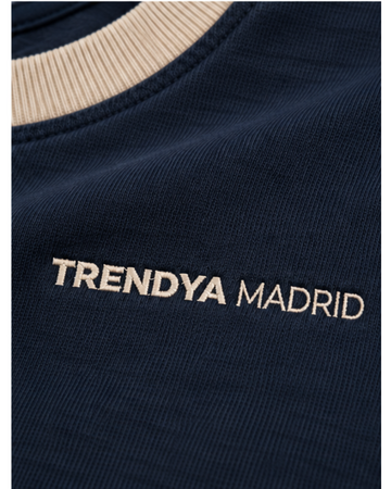 Detalle del cuello de canalé camel y del logotipo Trendya Madrid bordado sobre el azul marino