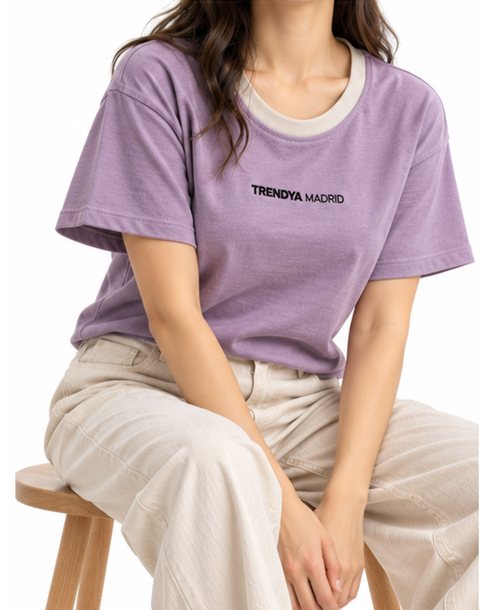 Camiseta corta de mujer lavanda con cuello gris piedra puesta, modelo sentada en un taburete